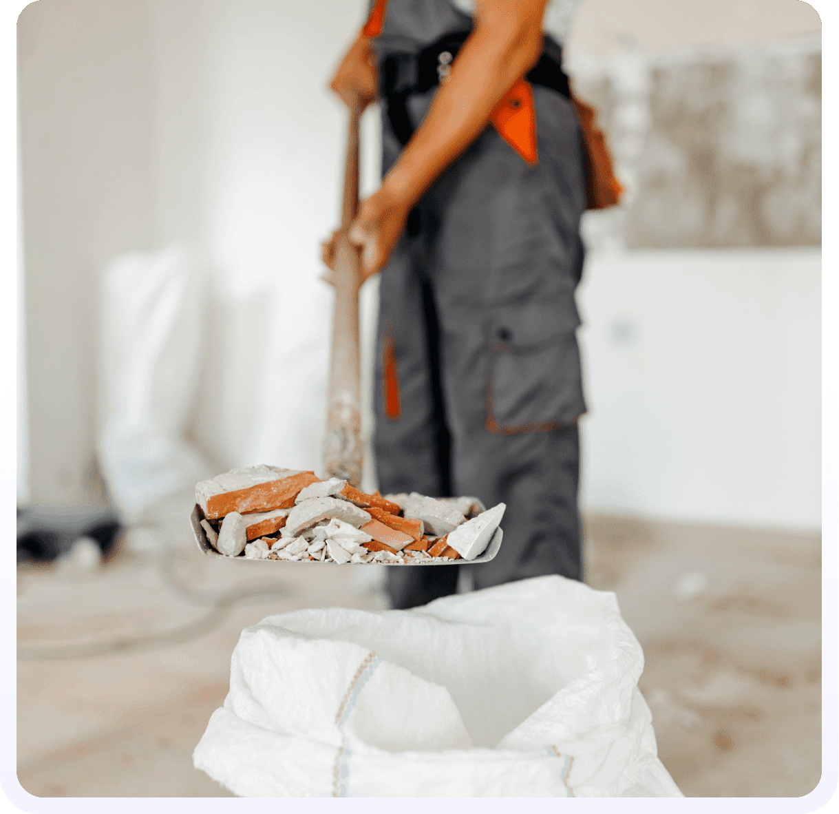 A person in an orange shirt and gray pants is holding a mop.