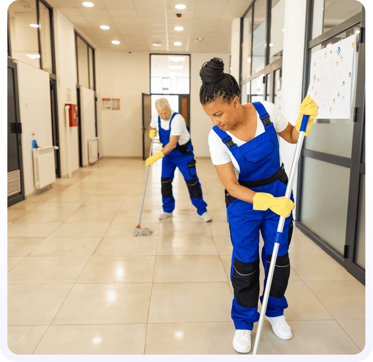 Two women in blue and white cleaning a floor.