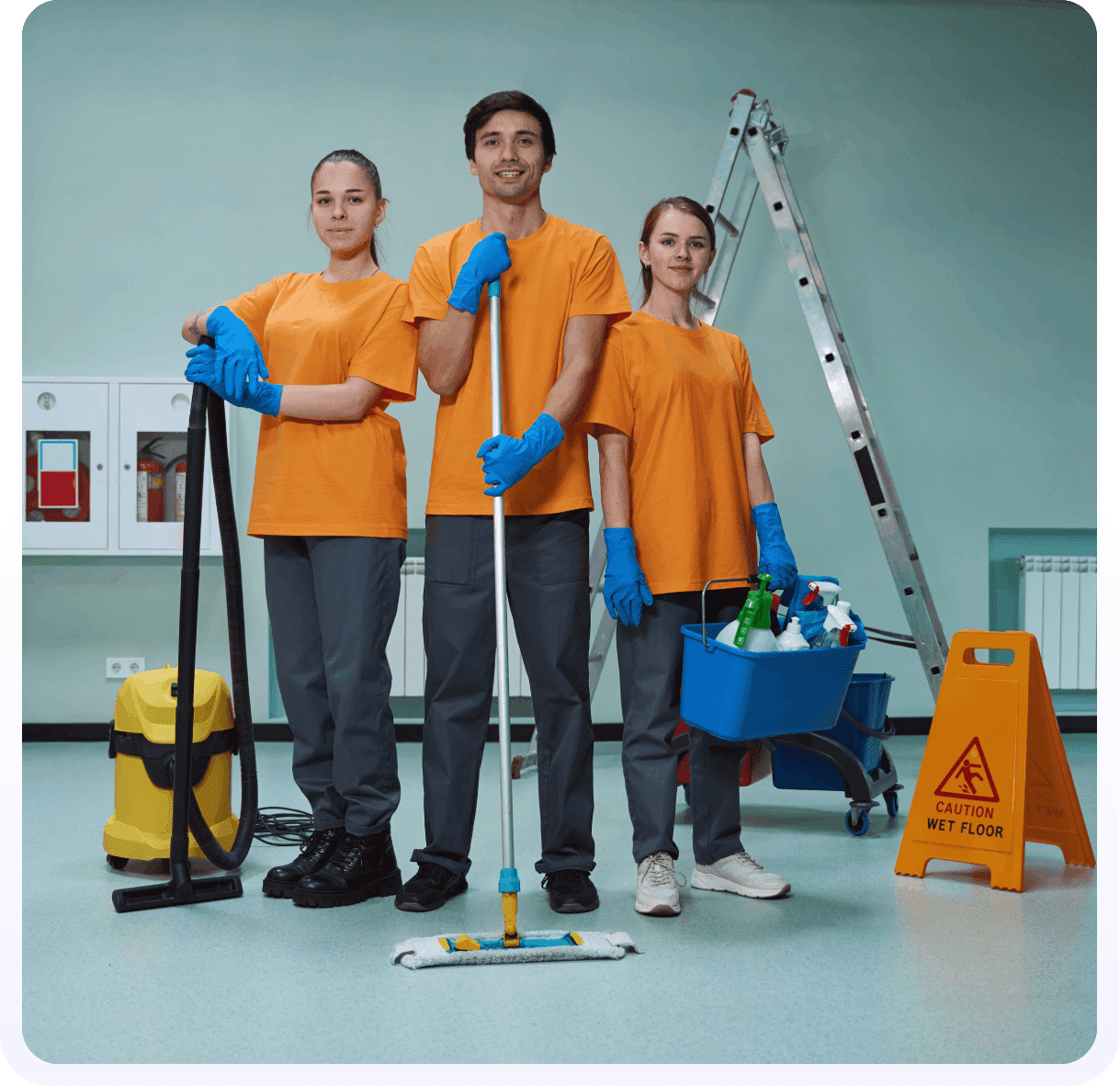Three people in orange shirts and blue gloves holding cleaning supplies.