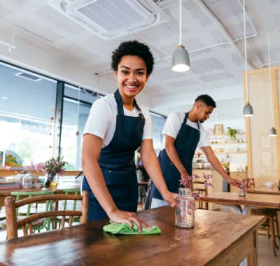 Two people are cleaning a table in an office.