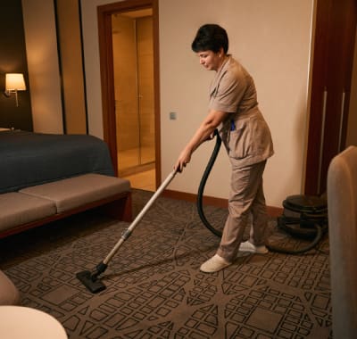 A person with a vacuum cleaner in the middle of a room.