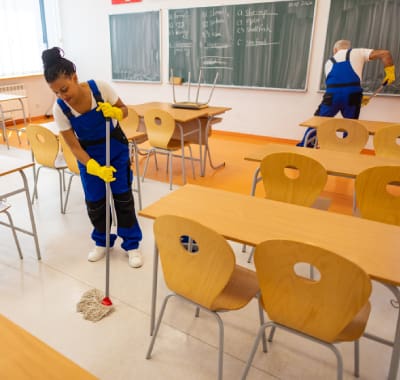 A woman in blue and yellow cleaning the floor.