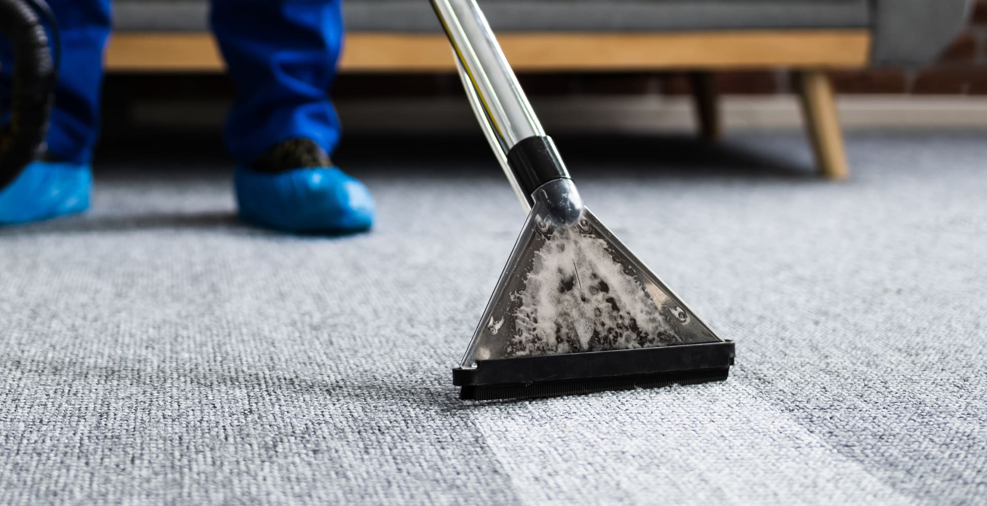 A person in blue pants and blue shoes is cleaning the floor.