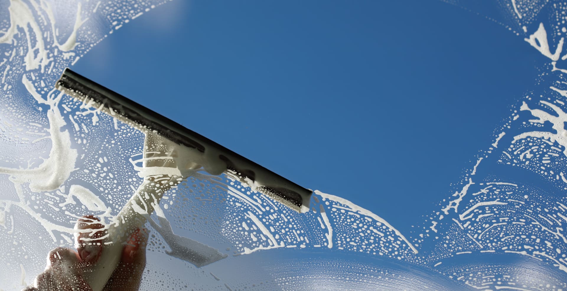 A person is holding onto the window of their car