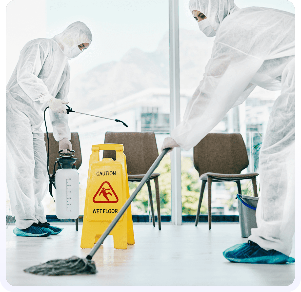 Two people in white suits cleaning a floor.