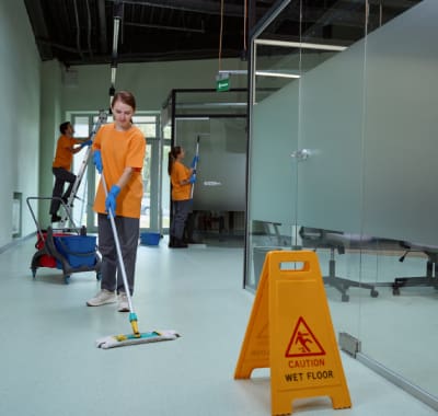 A man mopping the floor in an office building.