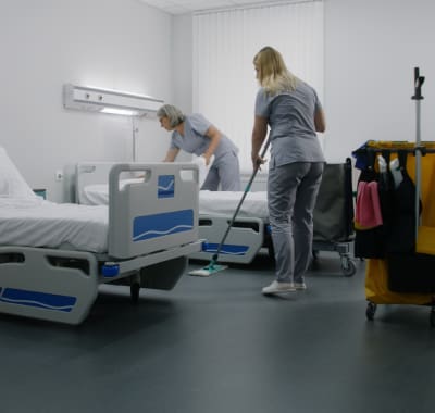 Two nurses are cleaning a hospital room.